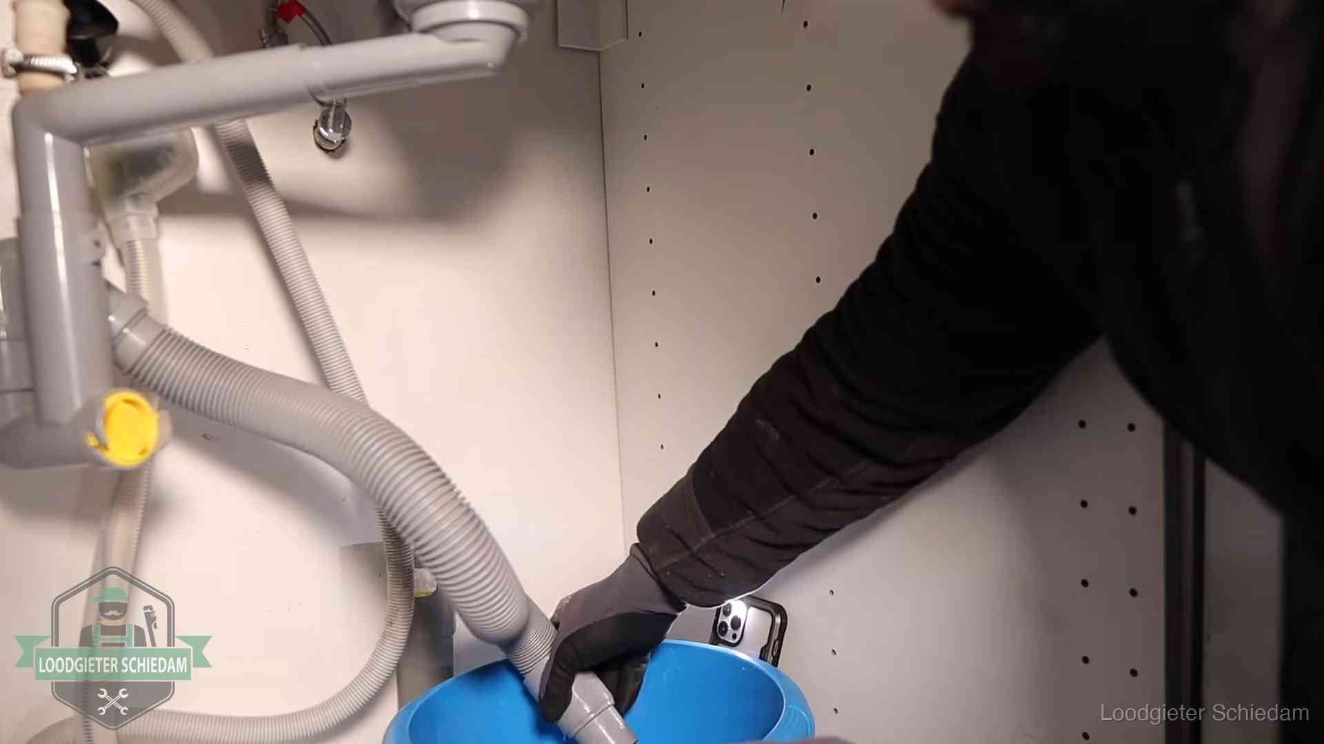 Afvoerslang loopt leeg in een emmer onder de gootsteen in Schiedam, een klus die je zelf kunt doen