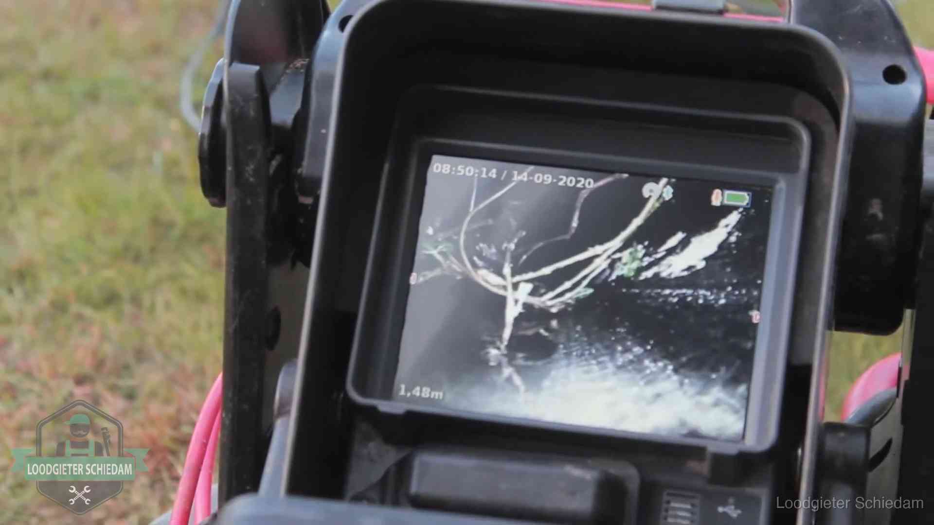 Monitor van een rioolcamera toont wortelingroei in de rioolbuis bij een woning in Schiedam