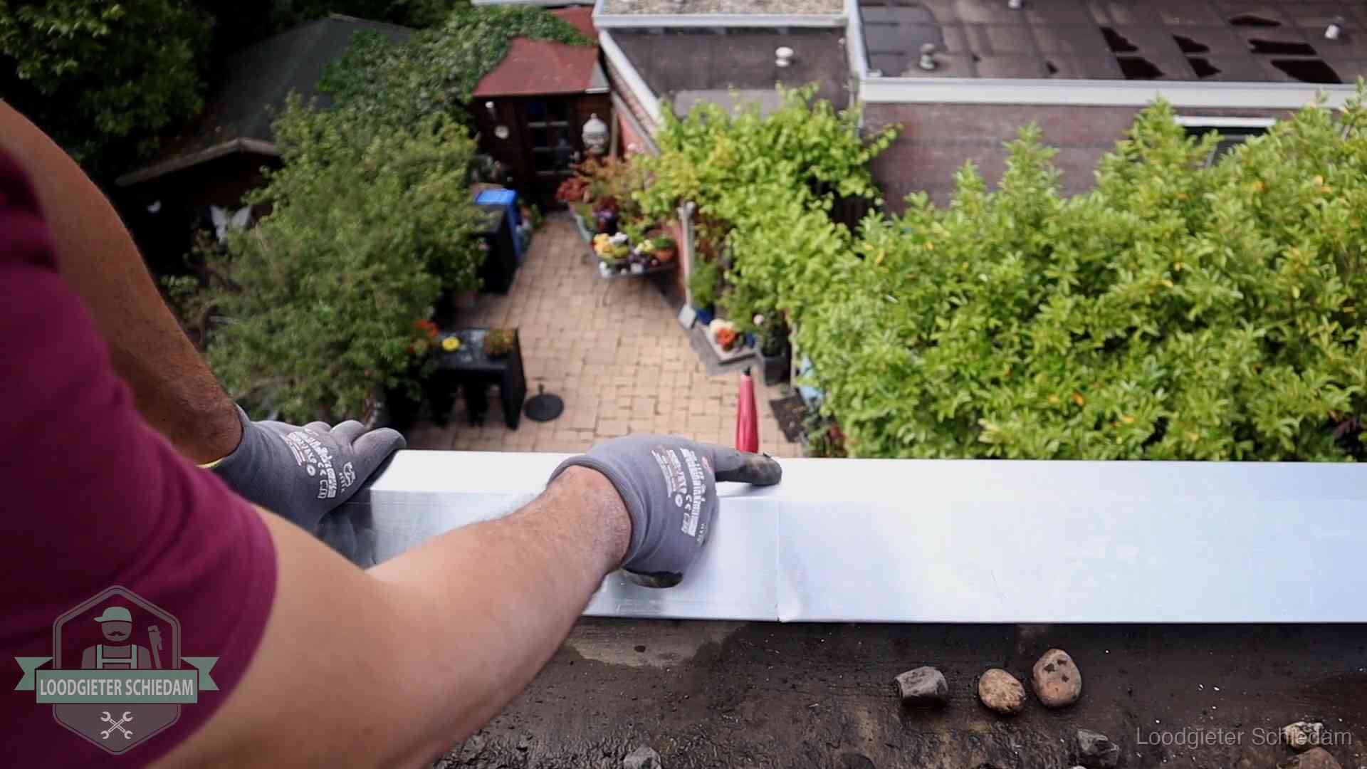 Daklekkage geregeld in Schiedam Vakman plaatst een daktrim op de dakrand van een woning in Schiedam