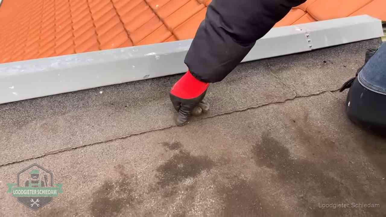 Lekkage bij de naad van een plat dak in Schiedam Vakman wijst een naad met vochtplekken aan op een bitumen plat dak in Schiedam