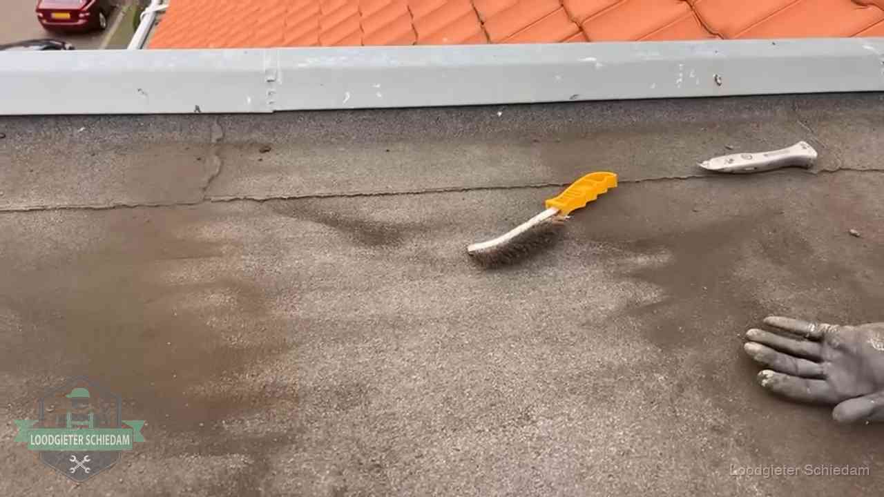 Kosten van daklekkage-reparatie in Schiedam Dakdekker bereidt een bitumen plat dak voor op reparatie bij de daktrim in Schiedam