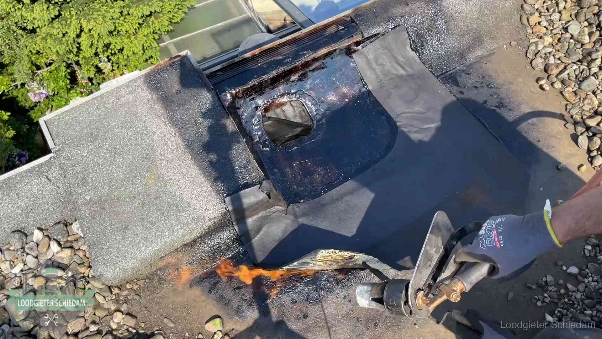 Daklekkage repareren in Schiedam Dakdekker brandt bitumen rond een doorvoer tijdens een daklekkage-reparatie in Schiedam