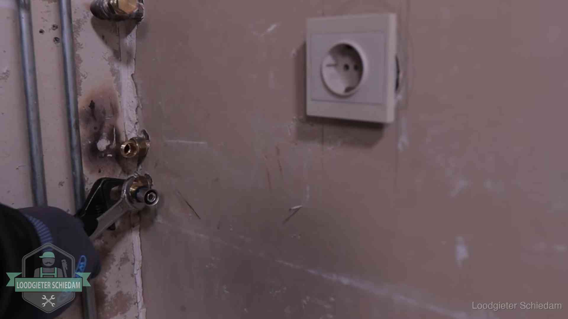 Monteur draait een perskoppeling vast op een leidingaansluiting in Schiedam