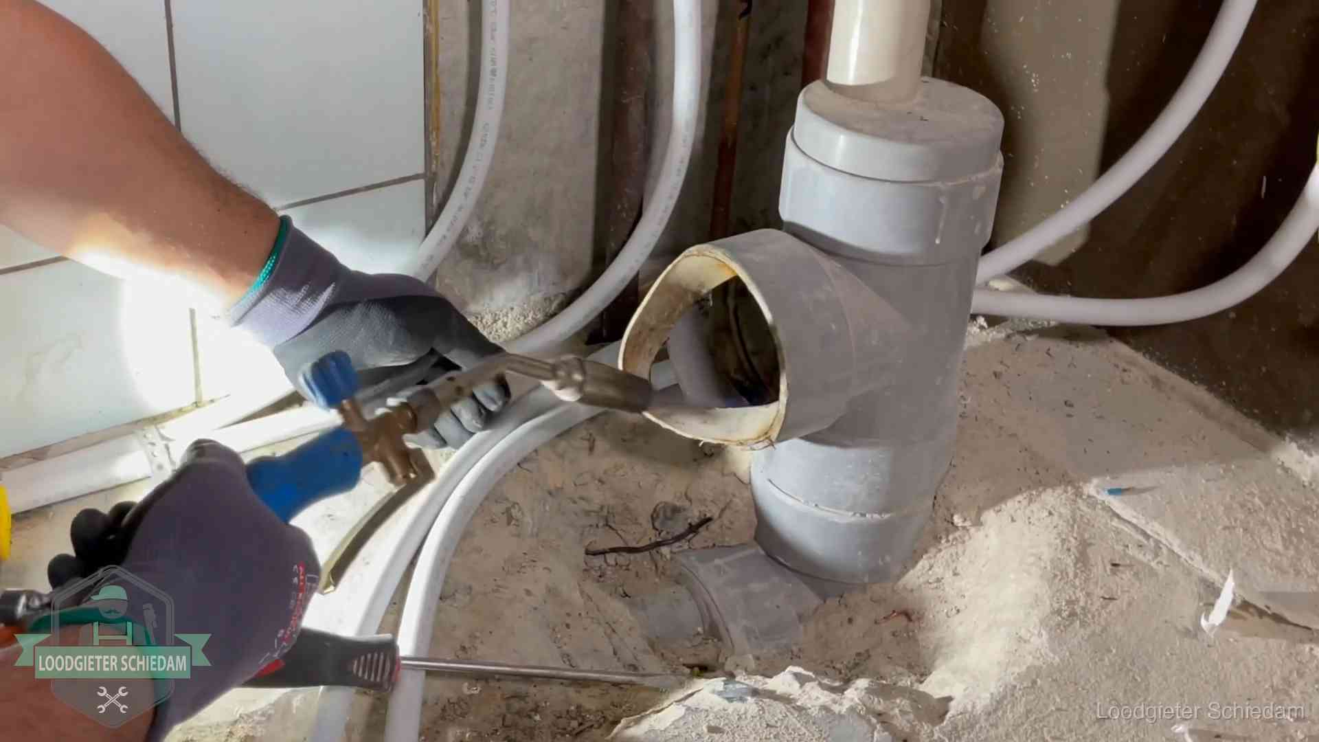 Loodgieter werkt met brander en messing kraanwerk aan leidingen in Schiedam