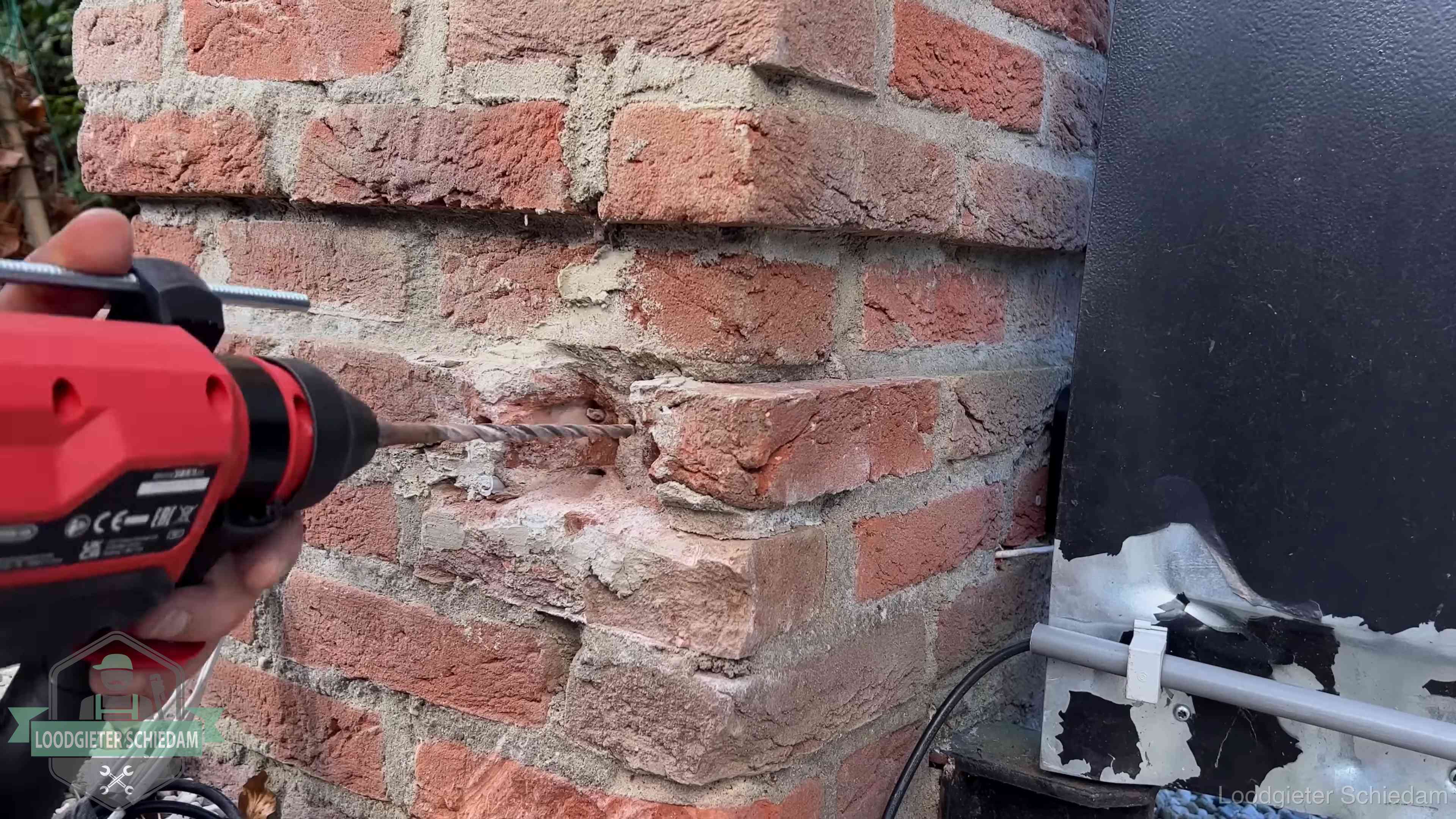 Vakman boort in de buitenmuur van een woning in de regio Schiedam