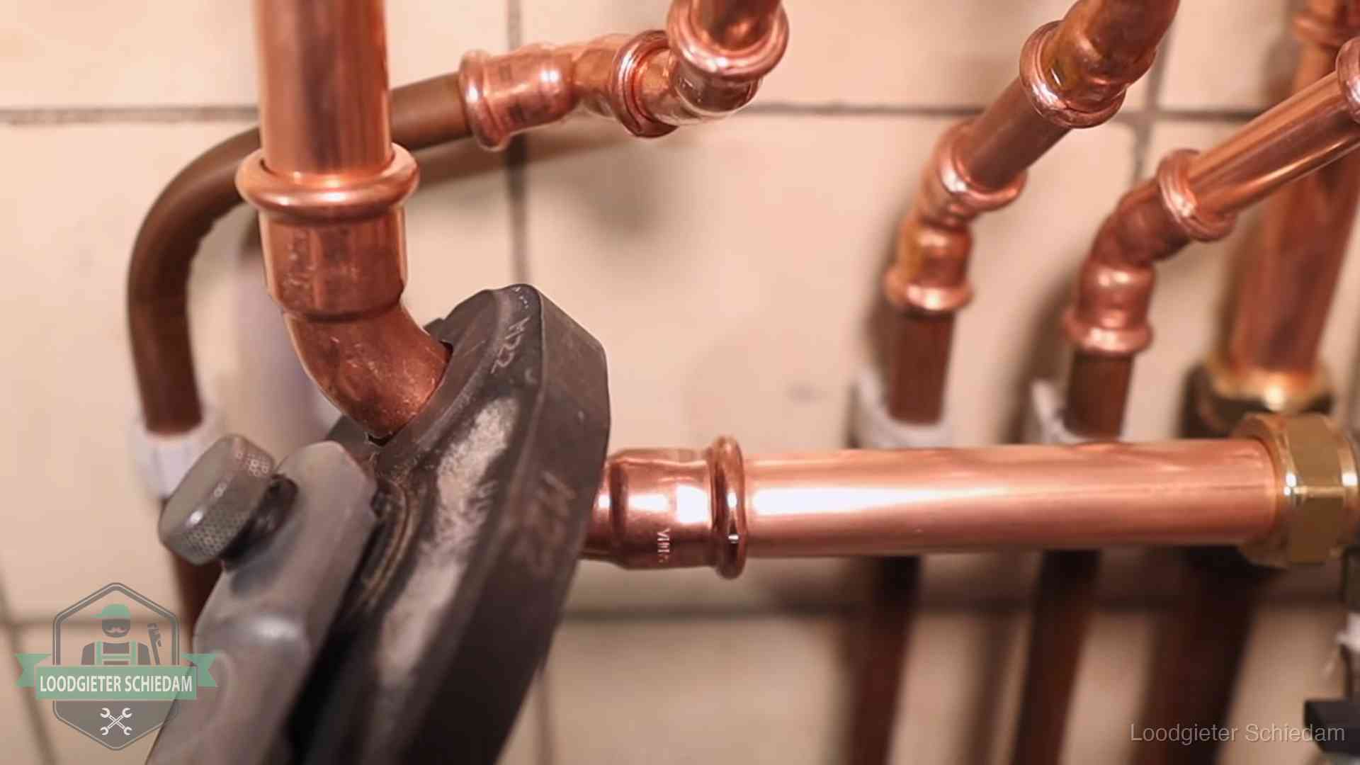 Persmachine perst een koperen fitting op nieuw leidingwerk in Schiedam