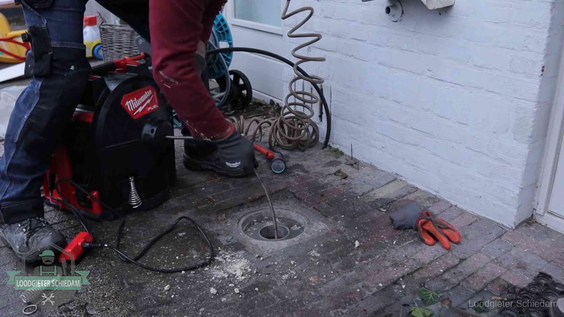 Spiraalmachine bij een ontstoppingsputje in de bestrating in Schiedam