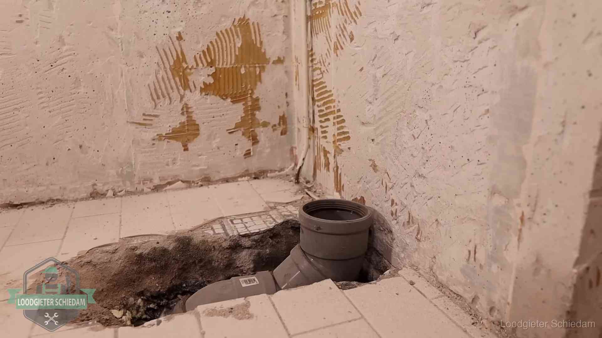 Opengebroken vloer met een nieuwe pvc-rioolbocht in een gegraven sleuf in Schiedam