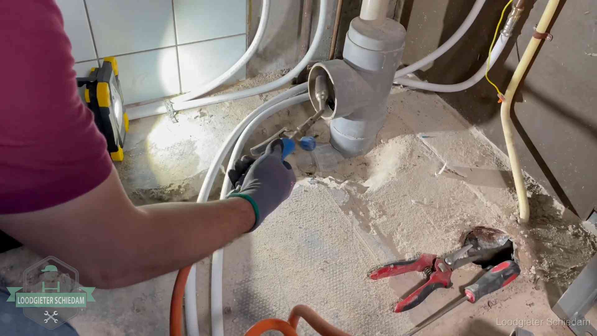 Loodgieter werkt aan leidingen bij een pvc-standleiding in een appartement in Schiedam