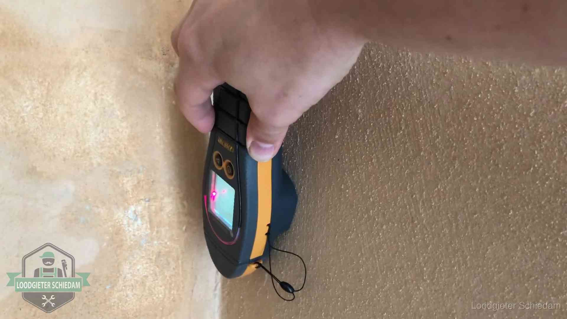Daklekkage opsporen zonder hakwerk in Schiedam Vochtmeter tegen een muur met vochtplekken tijdens het opsporen van een daklekkage in Schiedam